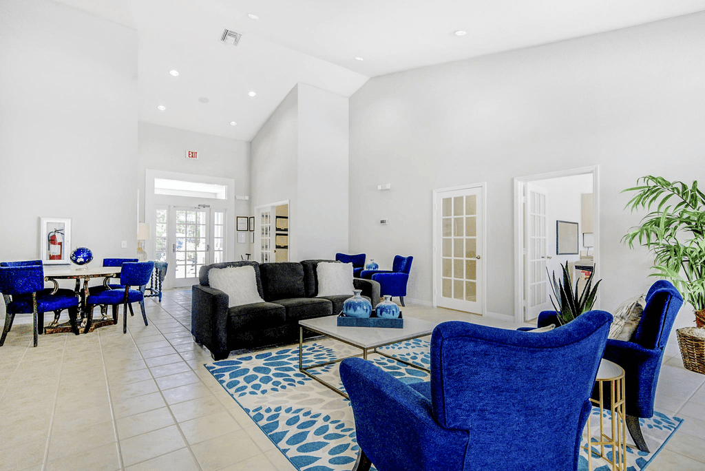 Interior of clubhouse featuring  welcoming  fabric chairs, couch, decorative pillows, coffee table with decor